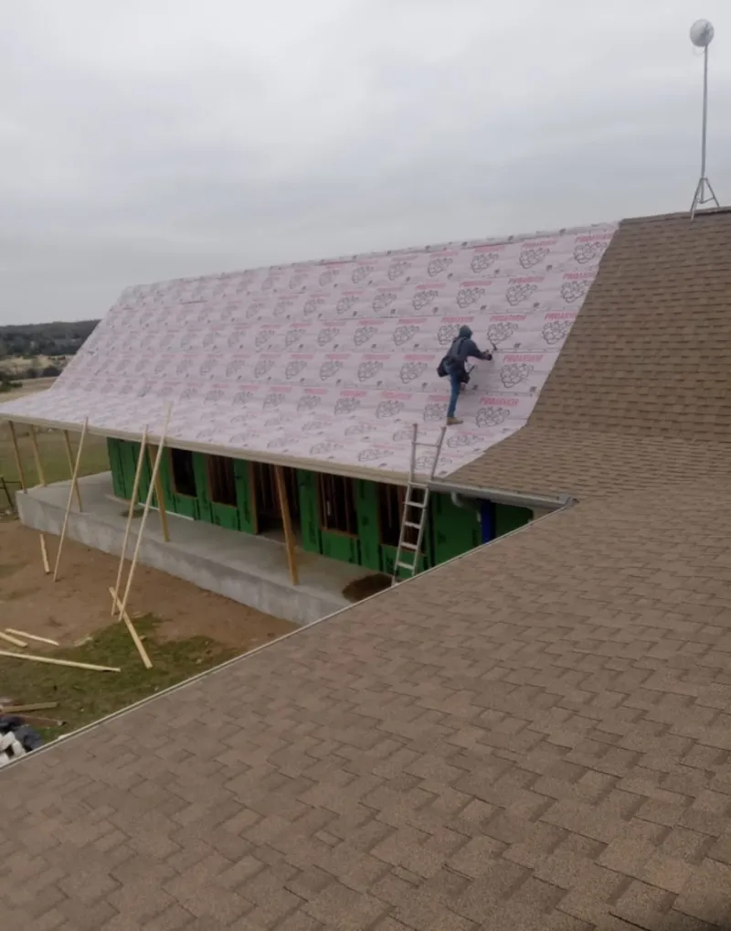 Worker preparing underlayment for a metal roof installation in Roanoke